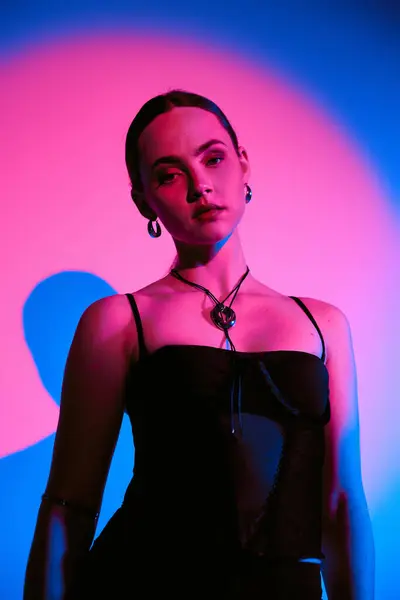 Enjoy the beauty of a young woman showcasing a trendy outfit illuminated by pink lighting. — Stock Photo
