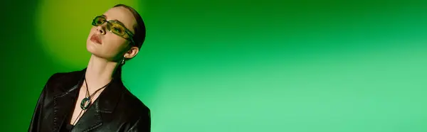 Una joven confiada en un elegante atuendo negro exuda estilo y sofisticación contra el verde vivo. - foto de stock