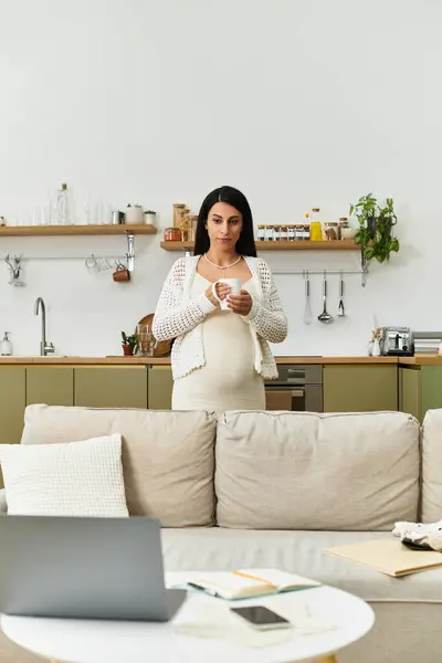 A pregnant woman enjoys a warm drink in her cozy modern kitchen. — Stock Photo