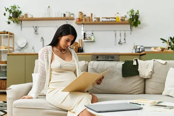Giovane madre in attesa si concentra su un libro nel suo elegante, caldo spazio abitativo, immerso nel verde. — Foto stock