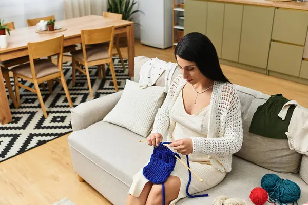 Una bella giovane donna che si gode la gravidanza mentre lavora abilmente a maglia in un soggiorno moderno. — Foto stock