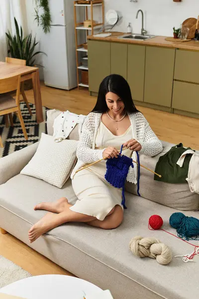 Eine junge, schöne werdende Mutter entspannt sich auf ihrem Sofa und strickt in ihrem stilvollen Zuhause. — Stockfoto