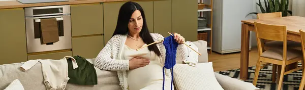 Expecting mother enjoys knitting a vibrant piece while feeling her baby move in a cozy lounge. — Stock Photo