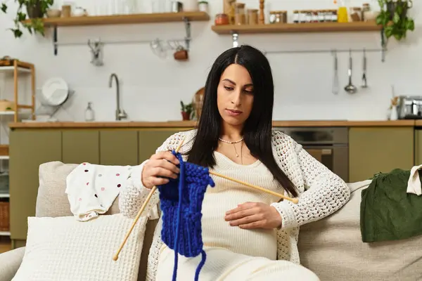 Young woman enjoying a peaceful moment crafting a knitted piece while expecting her baby. — Stock Photo