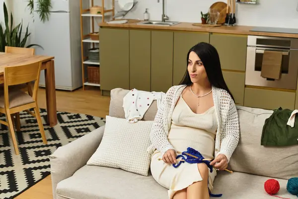 Pregnant woman relaxes on the couch, knitting and enjoying her home decor. — Stock Photo