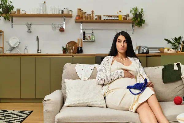 Hermosa joven, prominentemente embarazada, disfruta de su tiempo creativo en casa rodeada de calidez. - foto de stock