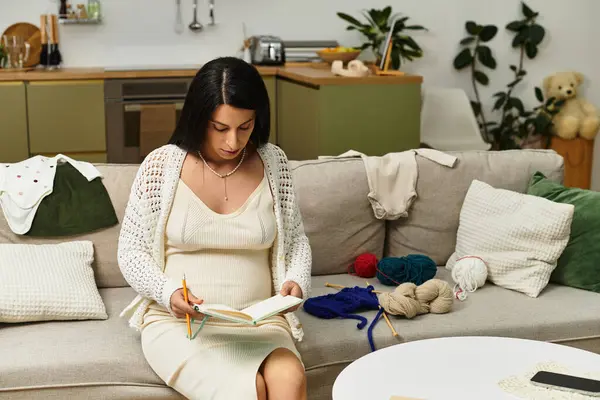 A glowing pregnant woman enjoys a moment of calm, noting down thoughts in her cozy living space. — Stock Photo