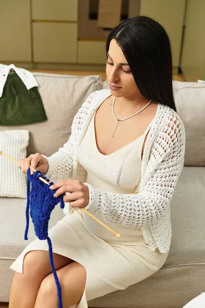 Young, beautiful woman expects a child, enjoying peaceful moments while knitting on the couch. — Stock Photo