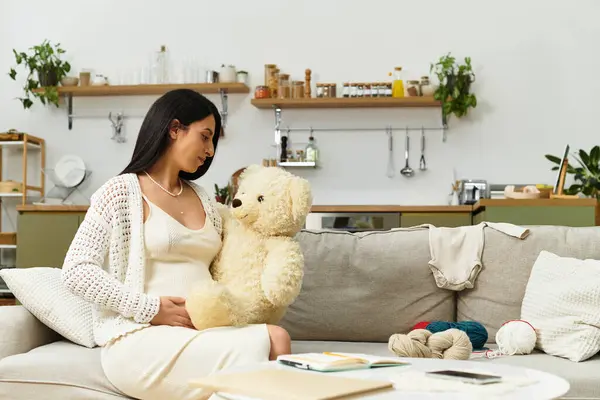 A young pregnant woman lovingly holds a teddy bear in a warm, inviting space. — Stock Photo