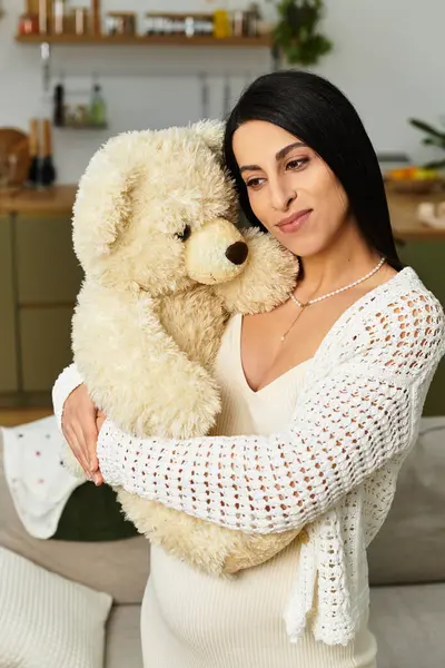 A young woman joyfully cradles a teddy bear, radiating warmth during her pregnancy. — Stock Photo