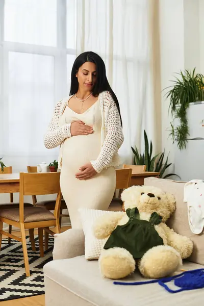A young, beautiful woman lovingly touches her pregnant belly, surrounded by home warmth and love. — Stock Photo