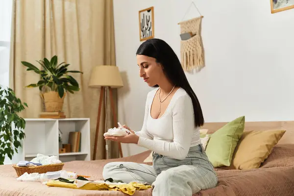 Werdende Mutter reflektiert ihre Reise, während sie Baby-Essentials in einem ruhigen Raum arrangiert. — Stockfoto