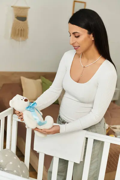 Junge Frau schätzt einen Teddybär, während sie ihr Kinderzimmer für einen Neuankömmling vorbereitet. — Stockfoto