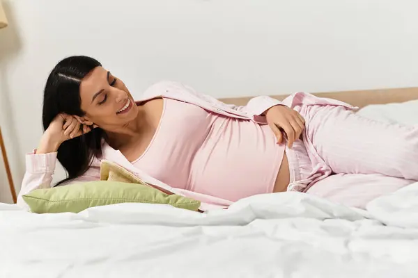 A young, beautiful woman happily relaxes on her bed, celebrating her pregnancy. — Stock Photo