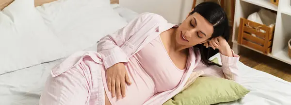 A serene young woman in pajamas enjoys a moment while awaiting her baby in a calm bedroom. — Stock Photo