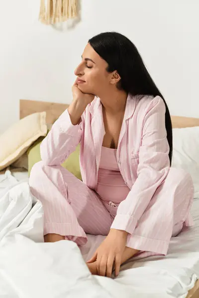 Young pregnant woman enjoys a serene moment of reflection while sitting calmly on her bed. — Stock Photo