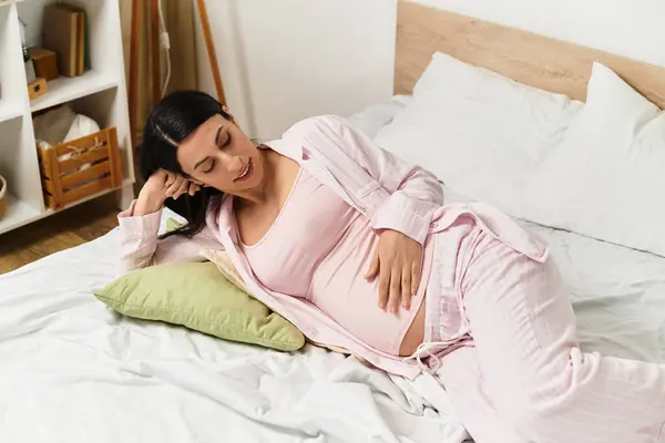 Young woman gently cradles her baby bump while enjoying a peaceful moment at home. — Stock Photo