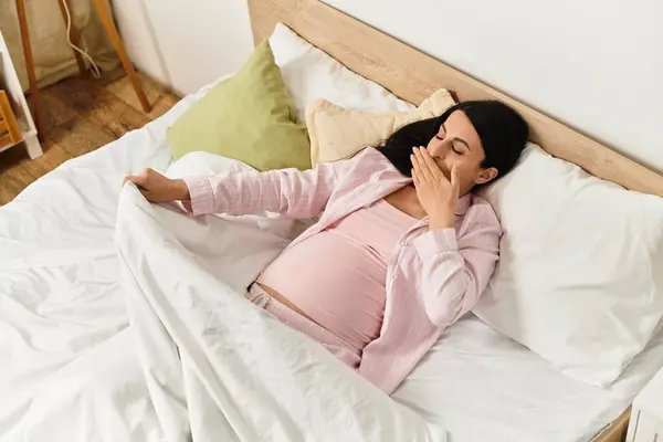 A serene moment as a young woman comfortably relaxes in bed, cherishing her pregnancy with calmness. — Stock Photo