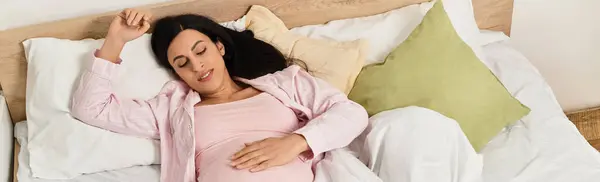 A young woman gently cradles her belly, immersed in serene thoughtfulness in a peaceful room. — Stock Photo