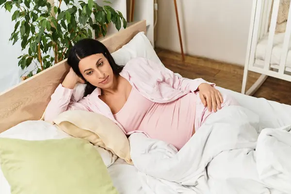 A beautiful pregnant woman relaxes in bed, surrounded by soft pillows and calm vibes. — Stock Photo