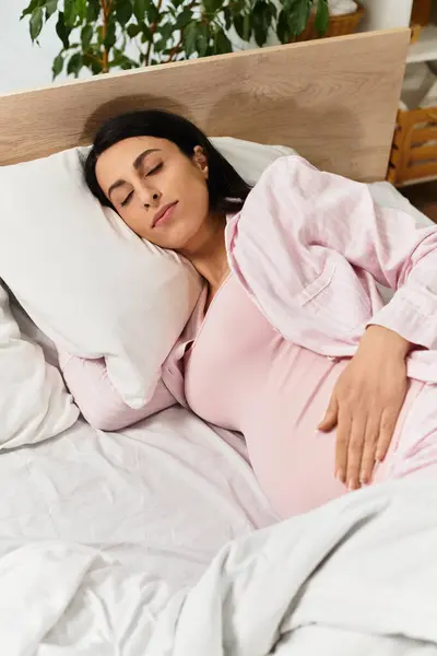 A young woman in pink relaxes on a bed, exuding calm and anticipation. — Stock Photo