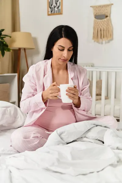 Young woman enjoys a cup in her cozy space, embracing her pregnancy. — Stock Photo