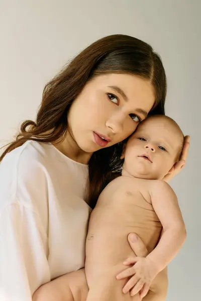 A young mother lovingly holds her naked baby in a warm, serene setting. — Stock Photo