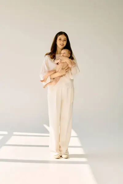 A young mother holds her baby close exuding love and warmth in a bright, minimalist space. — Stock Photo