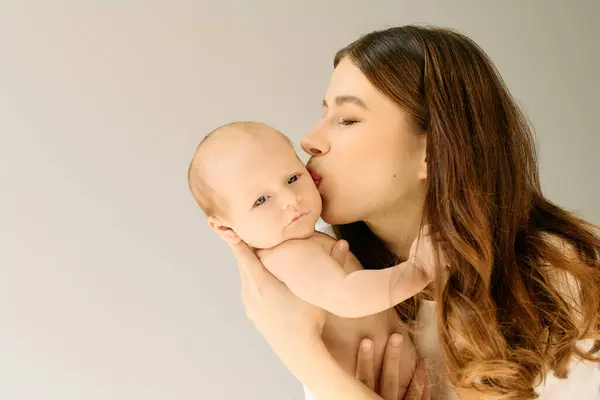 Una bella madre bacia amorevolmente il suo bambino, catturando un legame commovente tra loro.. — Foto stock
