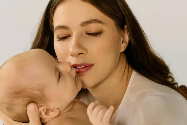 Una giovane madre guarda amorevolmente il suo bambino, condividendo un tenero momento di gioia e affetto. — Foto stock