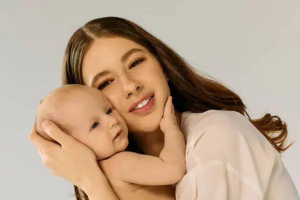 Una joven mujer con amor sostiene a su bebé, capturando un momento de corazón. - foto de stock