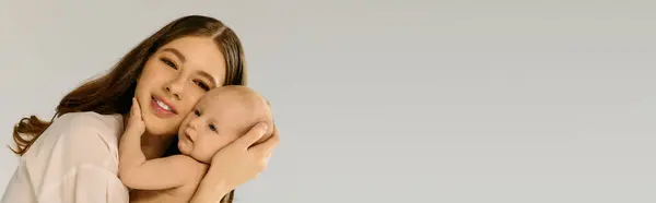 Une jeune mère tient amoureusement son enfant dans un contexte calme, rayonnant de joie. — Photo de stock