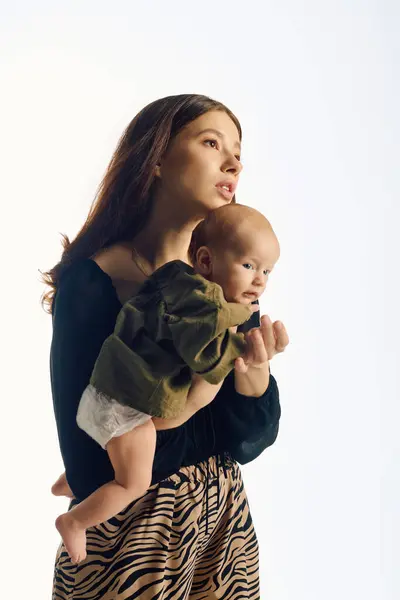 Una giovane madre tiene stretto il suo bambino, trasudando calore e cura in un ambiente moderno. — Foto stock