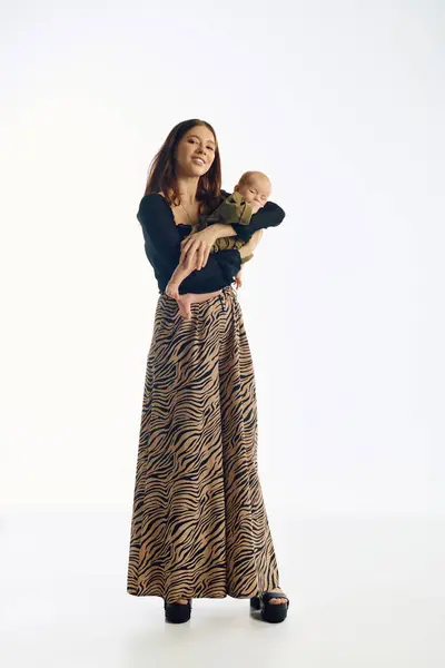 A young mother smiles lovingly as she gently holds her baby in a playful setting. — Stock Photo