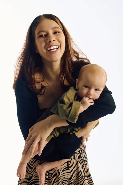 A joyful young mother holds her child, radiating love and connection. — Stock Photo