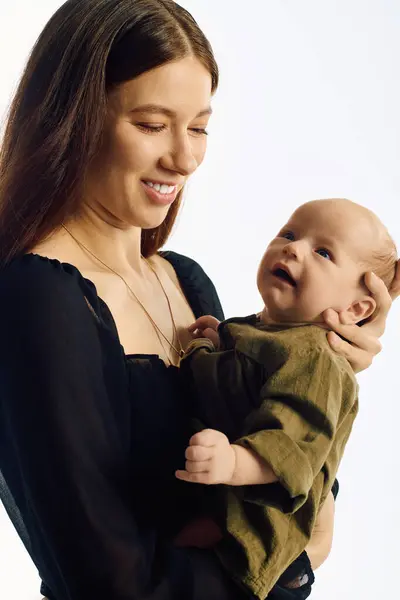 Questa bella giovane madre abbraccia il suo adorabile bambino con un sorriso caldo, mostrando gioia e amore. — Foto stock