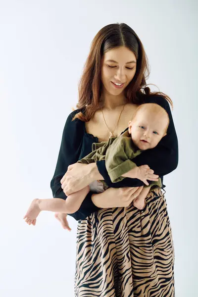 A beautiful young mother lovingly holds her little child, showcasing the bond of motherhood. — Stock Photo