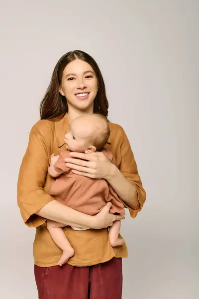 A young mother lovingly holds her baby, radiating warmth and happiness in a cozy atmosphere. — Stock Photo