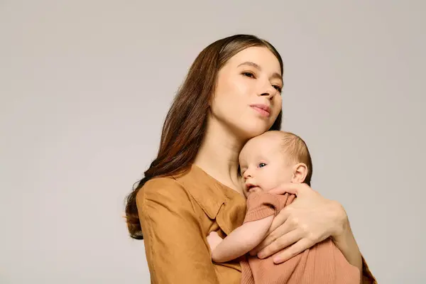 Una giovane madre culla il suo bambino, mostrando la bellezza dei legami familiari e la tenerezza. — Foto stock