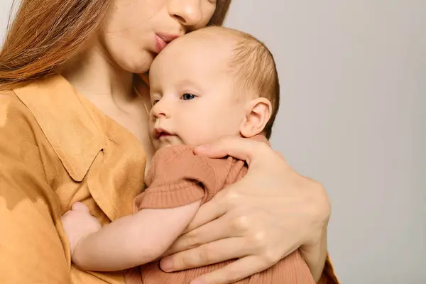 Una joven madre besa amorosamente a su hijo en un ambiente cálido y acogedor. - foto de stock