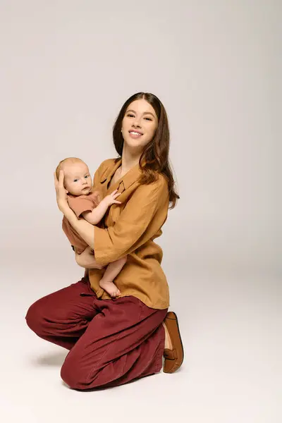 A joyful mother kneels with her happy infant, showcasing their warm, tender bond. — Stock Photo