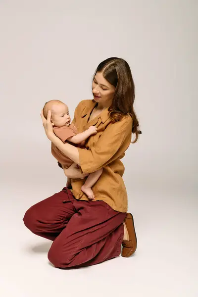Una giovane madre tiene amorevolmente il suo bambino, custodendo un momento speciale insieme in uno spazio calmo. — Foto stock
