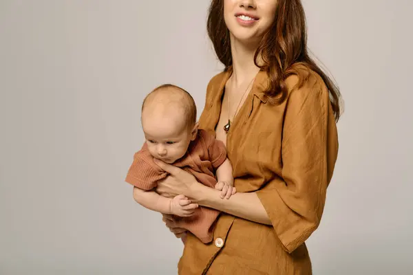 Una giovane madre stringe teneramente il suo bambino, evidenziando il loro legame familiare amorevole.. — Foto stock