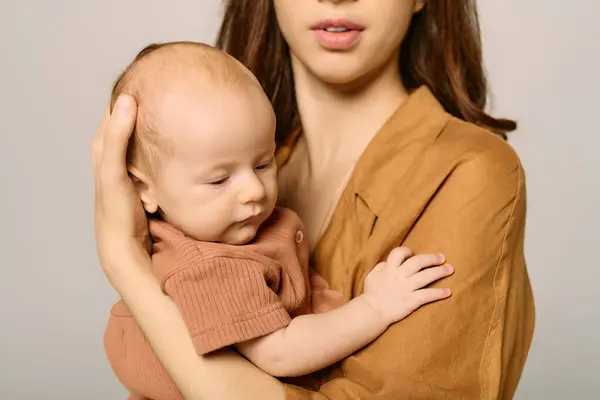 A young mother cradles her baby tenderly while sharing a moment of love in a cozy environment. — Stock Photo