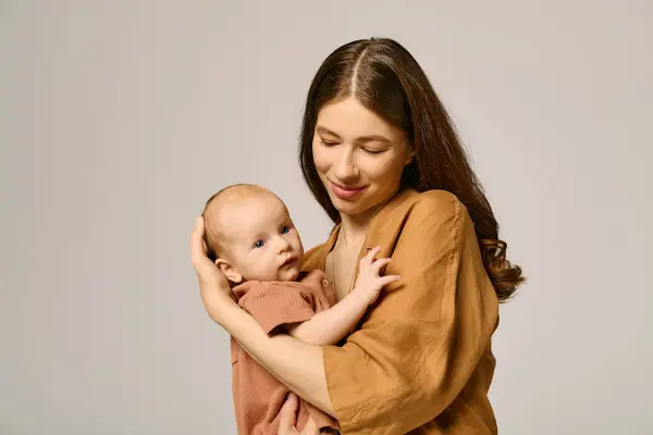Una giovane madre culla il suo prezioso bambino, entrambi condividendo sorrisi in un tenero momento d'amore. — Foto stock