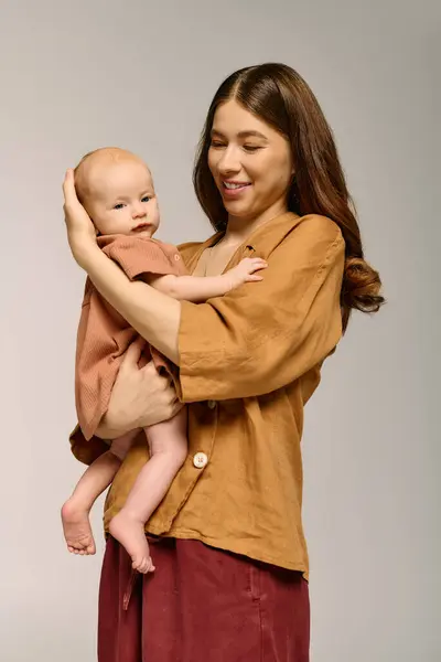 Una giovane madre abbraccia amorevolmente il suo bambino sorridendo in un momento caldo e gioioso di genitorialità. — Foto stock