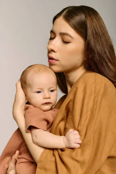 A young mother holds her baby close, radiating warmth and affection in a calm setting. — стоковое фото