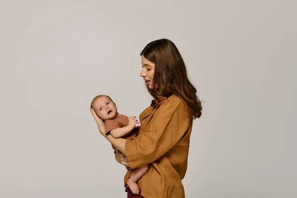 Une jeune mère tient avec amour son nouveau-né, affichant les joies de la parentalité. — Photo de stock