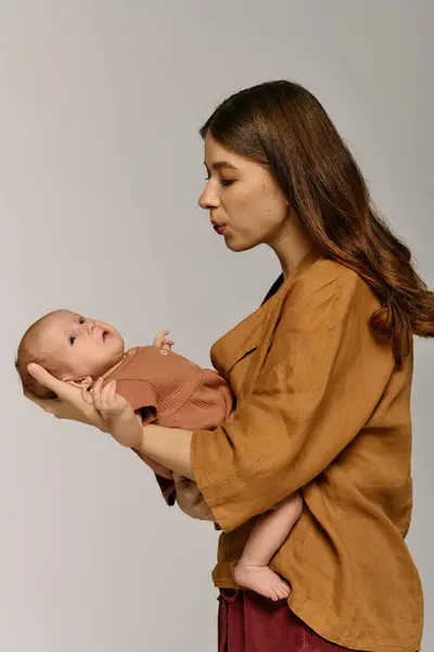 A young mother lovingly holds her infant, sharing a playful moment that captures family bonds. — Stock Photo