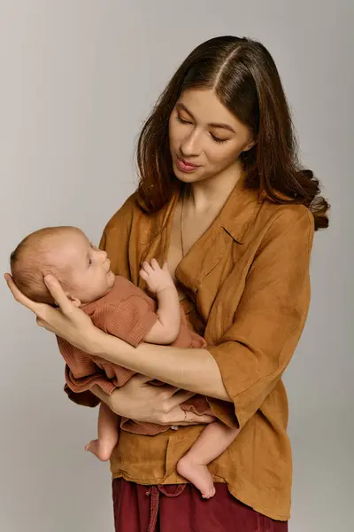 Una bella giovane madre stringe dolcemente il suo bambino, irradiando amore e calore nel momento. — Foto stock
